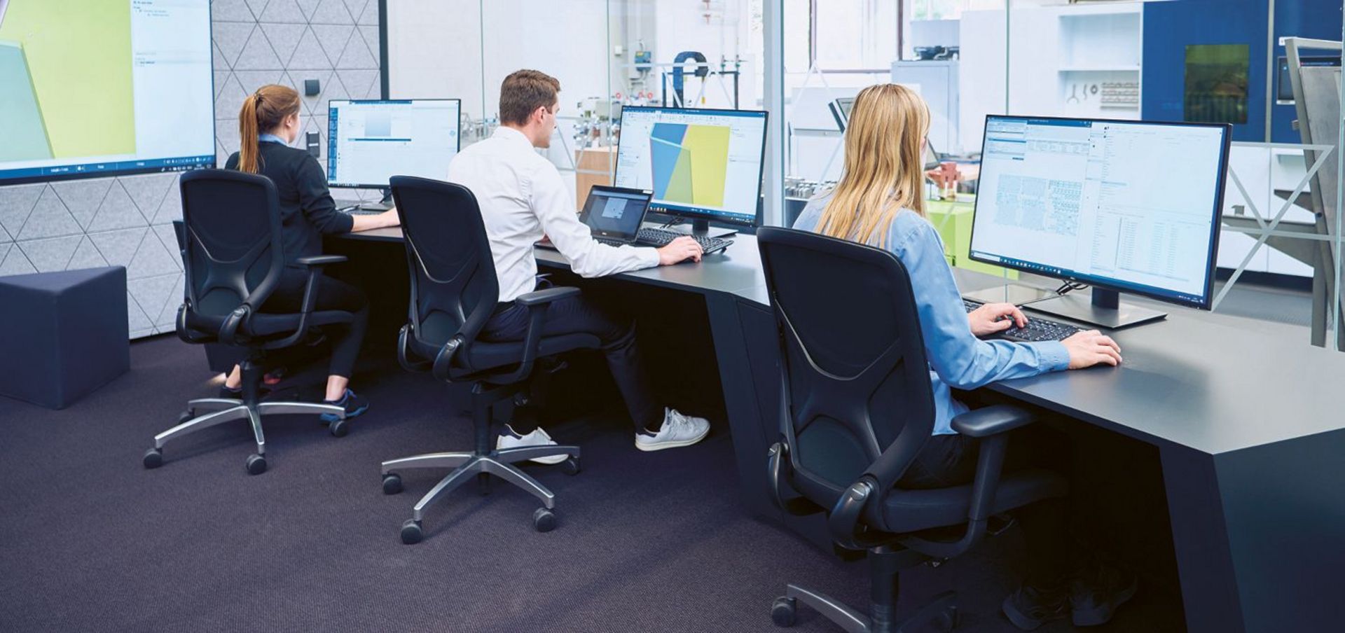 Drei Menschen sitzen vor Computern am Schreibtisch
