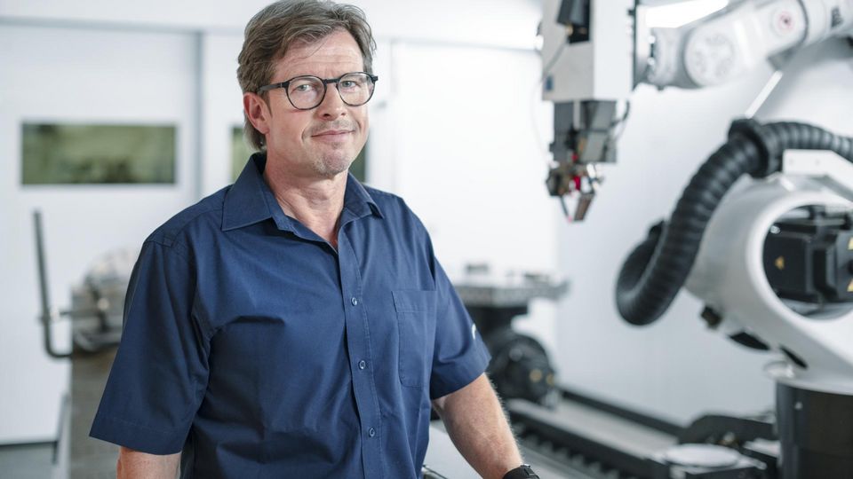 Geschäftsführer steht vor Laserschweißmaschine.