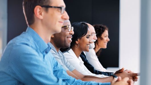 TRUMPF employees sitting in a row and laughing
