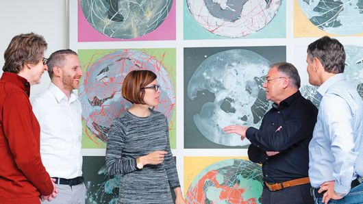 Angajați TRUMPF discută în fața unei picturi 